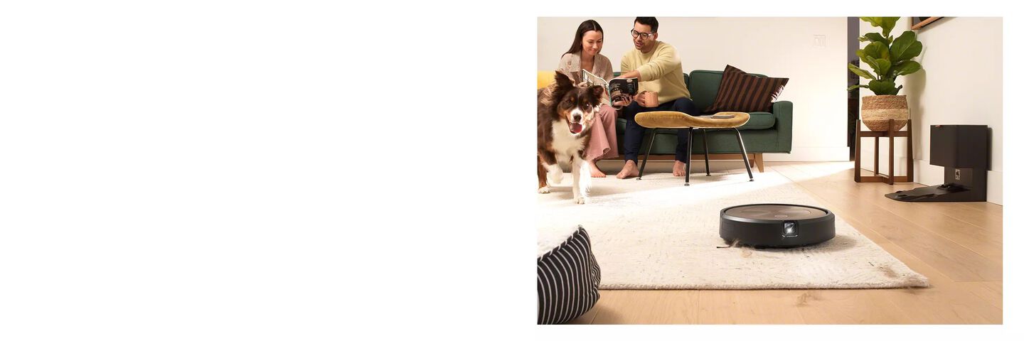 aspirador roomba recogiendo pelo de perro y una pareja y un perro en el fondo